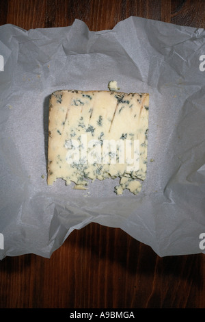 Stilton-Käse mit Papierverpackung auf Holzhintergrund Stockfoto