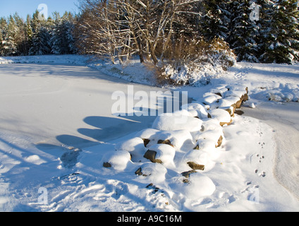 Verschneite Trittsteine über einen zugefrorenen Gartenteich, Finnland Stockfoto