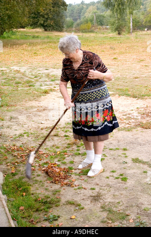 Urgroßmutter Laubrechen in sandigen Garten. Zawady Polen Stockfoto