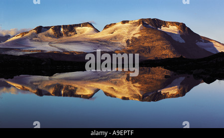 Licht des frühen Morgens auf den Gipfeln der Fannaraken mit einem Spiegel wie Spiegelung in einer eisigen See Jotunheim Region Norwegen Stockfoto