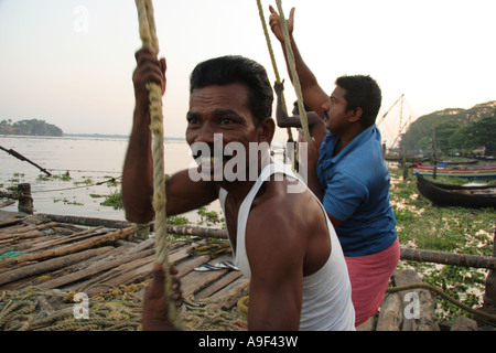 Fischer arbeiten zusammen, um die chinesischen Fischernetze in Kochi (Cochin), Kerala, Südindien zu heben Stockfoto