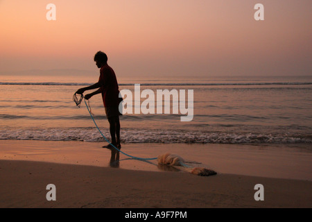 Lokale Fischer zieht in sein Netz in Palolem am Strand bei Sonnenaufgang in Süd-Goa, Indien Stockfoto