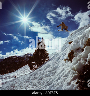 Snowboarder Snowboarden aus Felskante Gesicht durch die Luft, blauer Himmel und Wolken Stockfoto