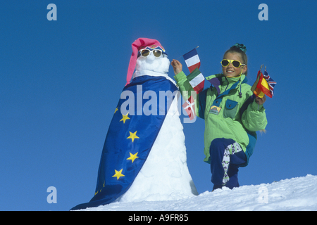 Mädchen mit Schneemann, geschmückt mit Fahnen der Europäischen Gemeinschaft. Stockfoto