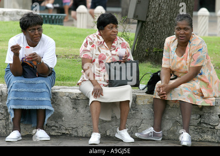 drei afroamerikanische Frauen nebeneinander auf einer Mauer sitzend. Stockfoto