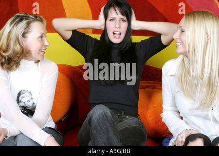 drei Frauen sitzen auf der Couch, eine Ihnen Platzierung Hände an ihren Ohren. Stockfoto
