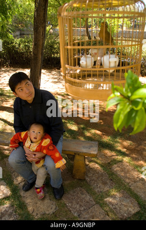 Lijiang junger Vater mit Kind beobachten im Käfig Vogel im Park, Provinz Yunnan, China Stockfoto