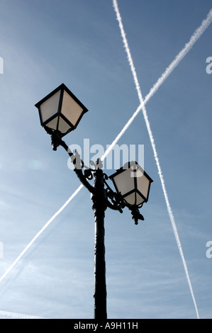 Flugzeuge jet trails Kreuz hoch über traditionelle Lamp Post in Villefranche, Cote d'Azur, Frankreich Stockfoto