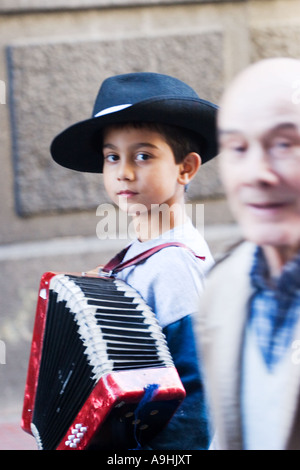 Greis, vorbei an einem sehr jungen Straßenmusiker mit einem Akkordeon in Buenos Aires Stockfoto