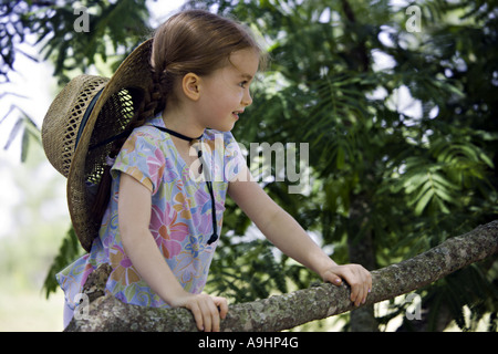SOUTH CAROLINA YORK schönes junges Mädchen mit Zöpfen blickt in die Ferne, als sie beim Sitzen auf einem Baum Mimosa träumt Stockfoto