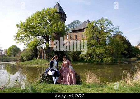 Junges Paar, gekleidet im Stil des Rokoko posiert vor der Wasserburg Linn, Krefeld, NRW, Deutschland Stockfoto