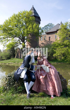 Junges Paar, gekleidet im Stil des Rokoko posiert vor der Wasserburg Linn, Krefeld, NRW, Deutschland Stockfoto