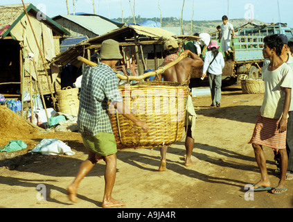 Fischer, die einen schweren Korb Fische auf eine Bambusstange schwimmenden Dorf Chong Kneas, Tonle Sap, Siem Reap, Kambodscha Stockfoto