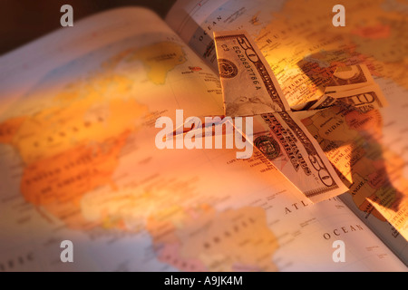 Flugzeug von Dollarnoten auf offenen Atlas gemacht Stockfoto