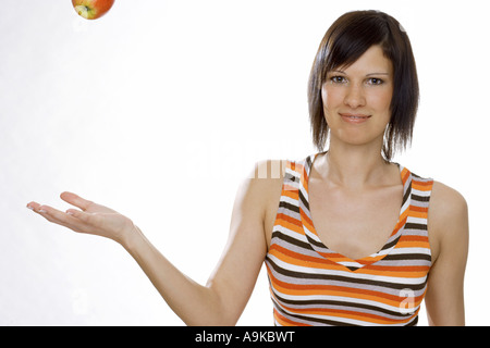 junge Frau wirft einen Apfel Stockfoto