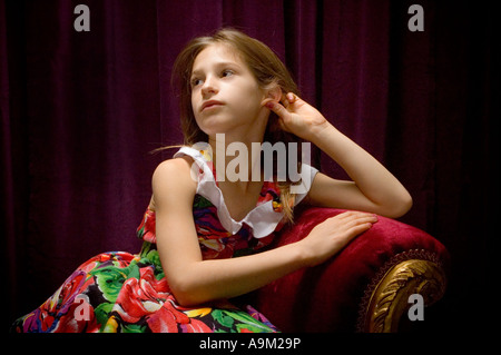 junges Mädchen posiert auf der roten Couch im studio Stockfoto