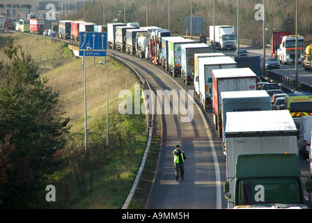 M25 Autobahn lange stationäre Warteschlange der Sattelzüge mit gelangweilt Fahrer zu Fuß auf Standstreifen Stockfoto