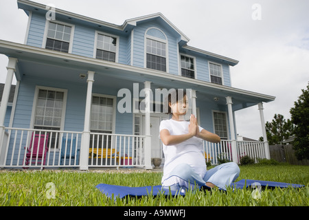 Schwangere Frau in einer Yogaposition vor Haus Stockfoto