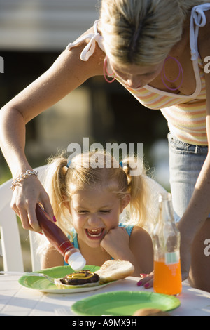 Eine Frau, ein junges Mädchen Burger Ketchup aufsetzen Stockfoto