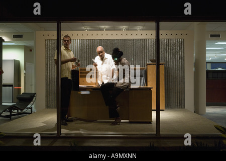 Drei Geschäftsleute in einem Büro auf ihren Mobiltelefonen Stockfoto