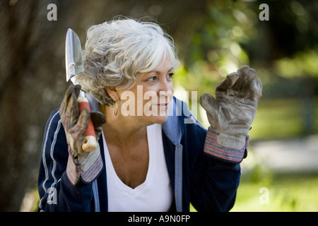 Nahaufnahme von Reife Frau mit Arbeitshandschuhen und hält ein Gartenarbeitwerkzeug Stockfoto
