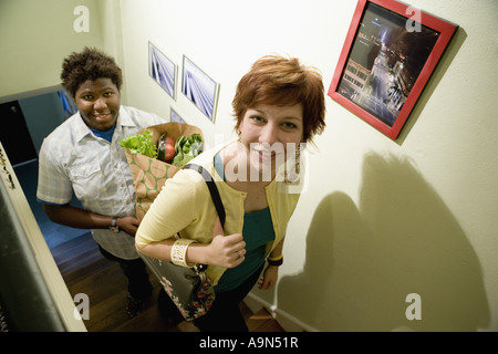 Porträt eines jungen Inter-racial Paares tragen Lebensmittel im Obergeschoss Stockfoto