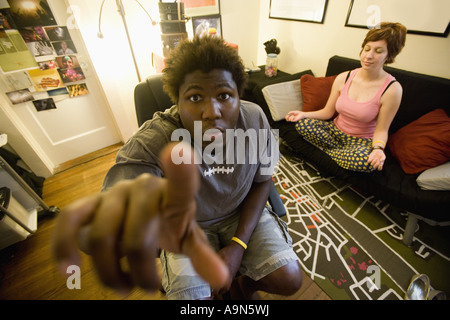 Afrikanischer Mann sitzen im Wohnzimmer, während Frau im Hintergrund meditiert Stockfoto
