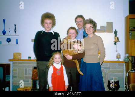 Familienporträt der 1970er Jahre im Wohnzimmer eines Wohnhauses: Eltern, zwei Jungen im Alter von 13 und 11 Jahren, ein vierjähriges Mädchen und ihre Ingwerkatze Stockfoto