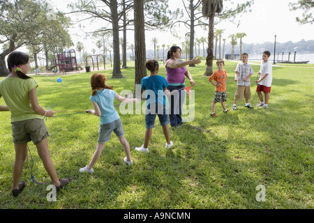 Drei Mädchen, drei Jungs in ein Tauziehen gepfiffen von ihrem Lehrer eine Herausforderung Stockfoto