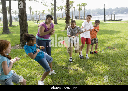 Drei Mädchen, drei Jungs in ein Tauziehen gepfiffen von ihrem Lehrer eine Herausforderung Stockfoto