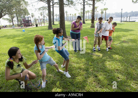 Drei Mädchen, drei Jungs in ein Tauziehen gepfiffen von ihrem Lehrer eine Herausforderung Stockfoto