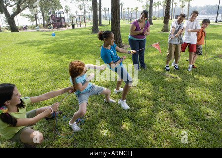 Drei Mädchen, drei Jungs in ein Tauziehen gepfiffen von ihrem Lehrer eine Herausforderung Stockfoto