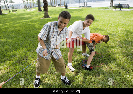 Drei Jungs zog hart an ein Tauziehen Stockfoto