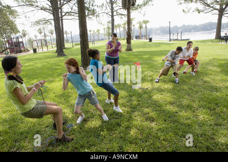 Drei Mädchen, drei Jungs in ein Tauziehen gepfiffen von ihrem Lehrer eine Herausforderung Stockfoto
