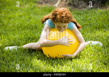 Mädchen liegen oben auf einem großen aufgeblasenen gelben ball Stockfoto