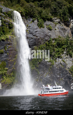 Sprudelnden Wasserfall Kaskaden durch Buchenwald im Fiordland Nationalpark in Neuseeland mit Touristen auf einem Sightseeing-trip Stockfoto