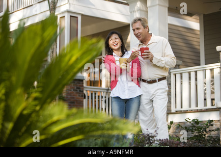 Liebevolle Reife Inter-racial paar Kaffeetassen vor ihrem Haus halten Stockfoto