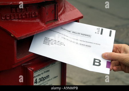 Umschlag mit Briefwahl in roten Briefkasten England Vereinigtes Königreich UK veröffentlicht Stockfoto