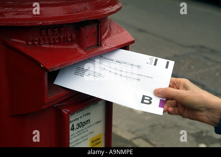 Umschlag mit Briefwahl in roten Briefkasten England Vereinigtes Königreich UK veröffentlicht Stockfoto