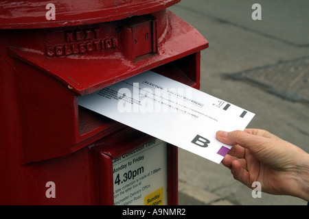 Umschlag mit Briefwahl in roten Briefkasten England Vereinigtes Königreich UK veröffentlicht Stockfoto