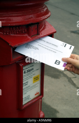 Umschlag mit Briefwahl in roten Briefkasten England Vereinigtes Königreich UK veröffentlicht Stockfoto