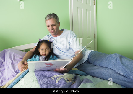 Vater mit Tochter Lesebuch im Schlafzimmer Stockfoto