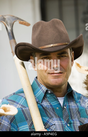 Reifer Mann Cowboy Hut hält eine Schaufel Stockfoto