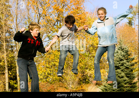 Drei springenden Kinder in der Luft mit Herbstlaub Stockfoto