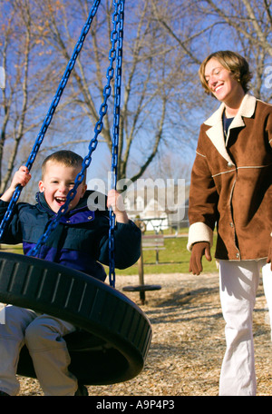 Frau drücken kleiner Junge auf Reifenschaukel Stockfoto