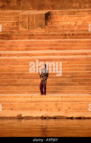 Mann am Ufer des Flusses Ganges, Varnasi, Indien Ghat Schritten Flötenspiel Stockfoto