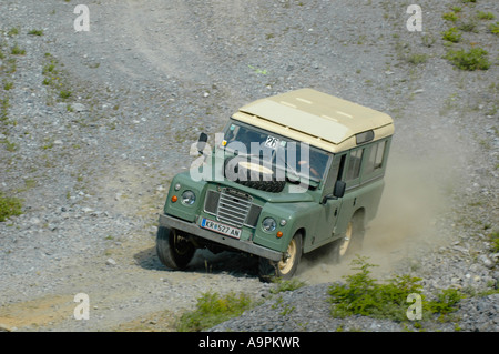 1970 s Land Rover Series 3 109 LWB Kombi 4cyl Benzin Beschleunigung entlang einer Schotterpiste auf der Boesenstein Offroad Classic verfolgen. Stockfoto