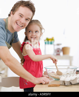 Vater und Tochter mischen Teig in Küche Stockfoto