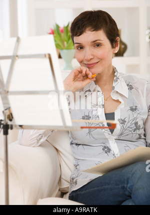 Frau sitzt neben Noten auf Ständer Stockfoto