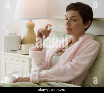 Frau, die eigene Temperatur im Bett Stockfoto